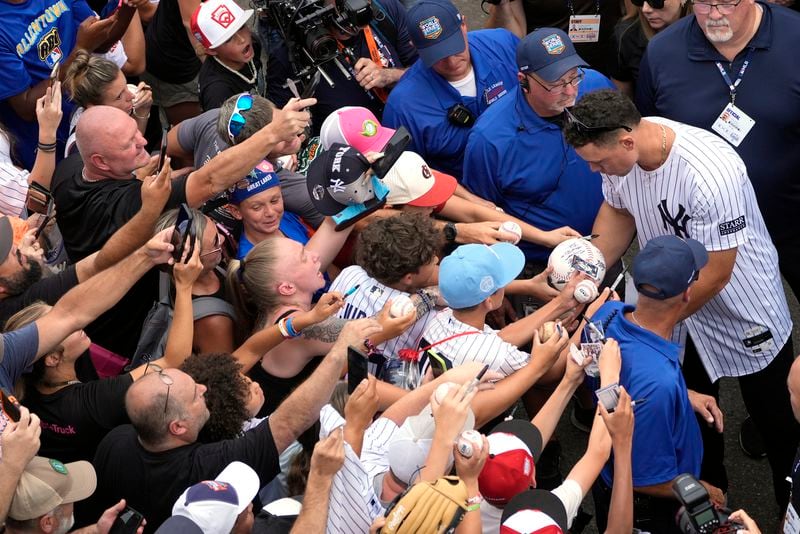 New York Yankees' Aaron Judge signs autographs for fans as the New York Yankees arrive at the Little League World Series Complex to watch the Little League World Series tournament in South Williamsport, Pa., Sunday, Aug. 18, 2024. (AP Photo/Tom E. Puskar)