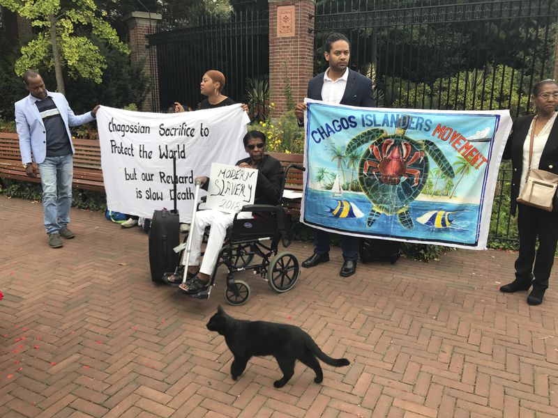 FILE - Protesters hold banners outside the World Court in The Hague, Netherlands, Monday, Sept. 3, 2018, where judges listen to arguments in a case on whether Britain illegally maintains sovereignty over the Chagos Islands. (AP Photo/Mike Corder, File)