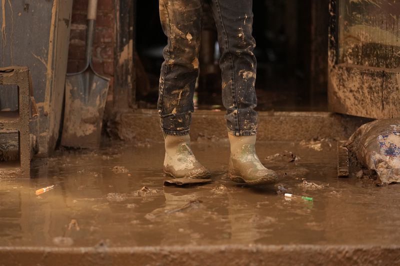 Eva Markowitz stands covered in mud left by Hurricane Helene as she works to clean up Zadie's Market and Deli Tuesday, Oct. 1, 2024, in Marshall, N.C. (AP Photo/Jeff Roberson)