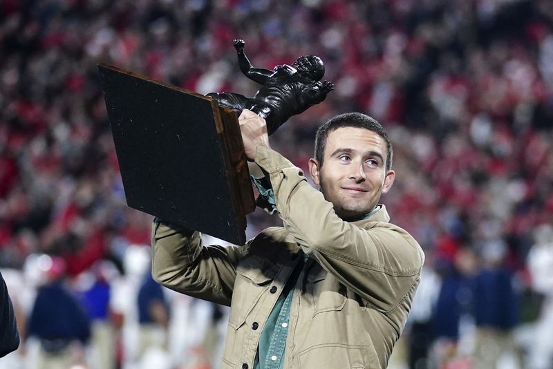 Former Georgia and current Los Angeles Rams quarterback Stetson Bennett holds a trophy as he is honored during the first half of an NCAA college football game between Mississippi and Georgia, Saturday, Nov. 11, 2023, in Athens, Ga. (AP Photo/John Bazemore)