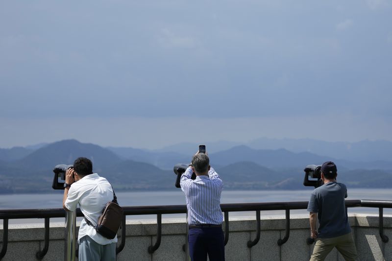 Visitors use binoculars to see the North Korean side from the unification observatory in Paju, South Korea, Tuesday, June 25, 2024. South Korea threatened Tuesday to restart anti-Pyongyang frontline propaganda broadcasts in the latest bout of Cold War-style campaigns between the rivals after North Korea resumed its trash-carrying balloon launches. (AP Photo/Lee Jin-man)