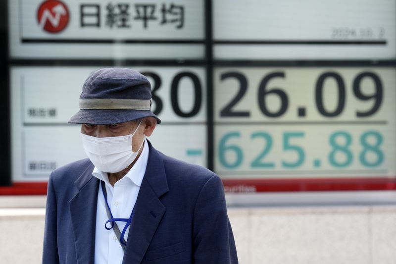 A person walks in front of an electronic stock board showing Japan's Nikkei index at a securities firm Wednesday, Oct. 2, 2024, in Tokyo. (AP Photo/Eugene Hoshiko)