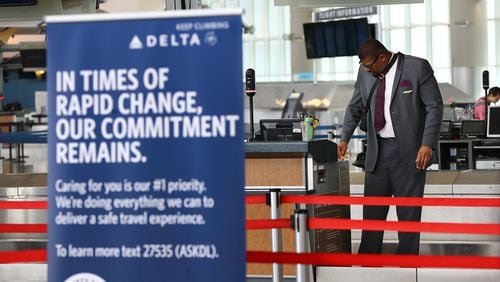 A Delta ticket agent cleans his work station while waiting for passengers in Atlanta Hartsfield-Jackson’s international terminal on Monday, March 30, 2020, in Atlanta. Curtis Compton ccompton@ajc.com
