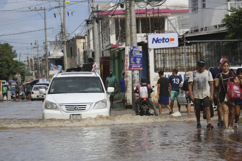 Residents walk on a flooded street in the aftermath of Hurricane John in Acapulco, Mexico, Saturday, Sept. 28, 2024. (AP Photo/Bernardino Hernandez)