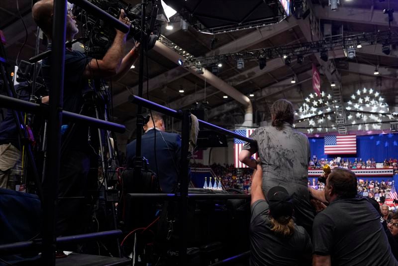 Police and security remove a man, right center, who had climbed over barricades and onto the media riser, as Republican presidential nominee former President Donald Trump speaks at a campaign event, Friday, Aug. 30, 2024, in Johnstown, Pa. (AP Photo/Alex Brandon)