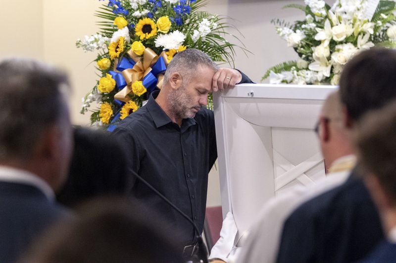 Dorin Irimie, husband of Ana Cristina Irimie, a math teacher killed during a shooting at Apalachee High School, mourns by her casket at her funeral service at Hamilton Mill Memorial Chapel and Gardens in Buford, Ga., on Saturday, Sept. 14, 2024. (Arvin Temkar/Atlanta Journal-Constitution via AP)