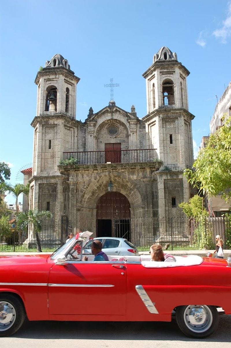 A restored American car passes in front of Santo Christo church in Old Havana. PHOTO CREDIT: Bill Osinski