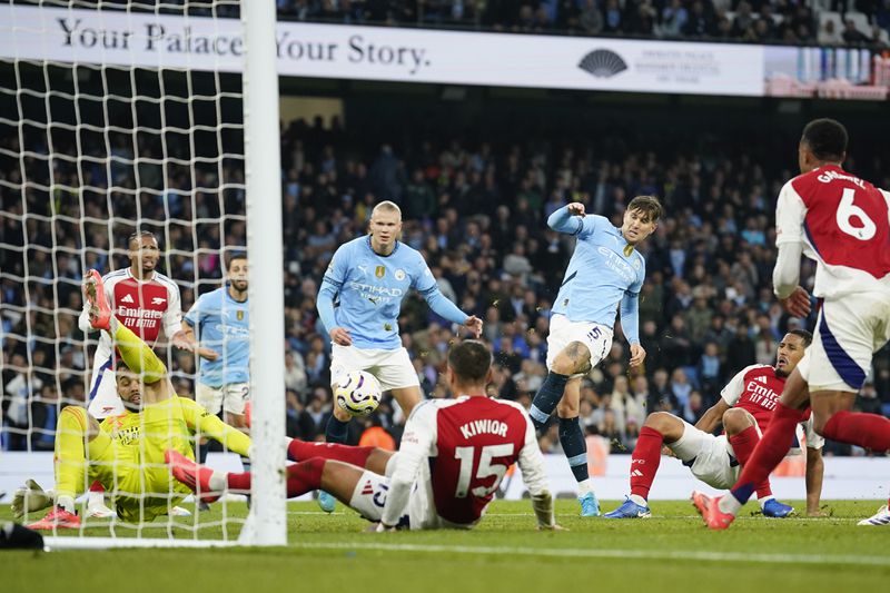 Manchester City's John Stones, center, scores his side's second goal during the English Premier League soccer match between Manchester City and Arsenal at the Etihad stadium in Manchester, England, Sunday, Sept. 22, 2024. (AP Photo/Dave Thompson)