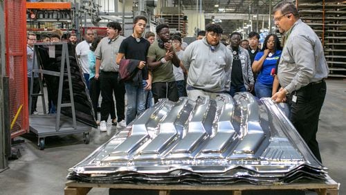 Vice President of Operations Chris Fann (right) shows a product to high school students at Lund International in Lawrenceville on Thursday, Oct. 3, 2019.