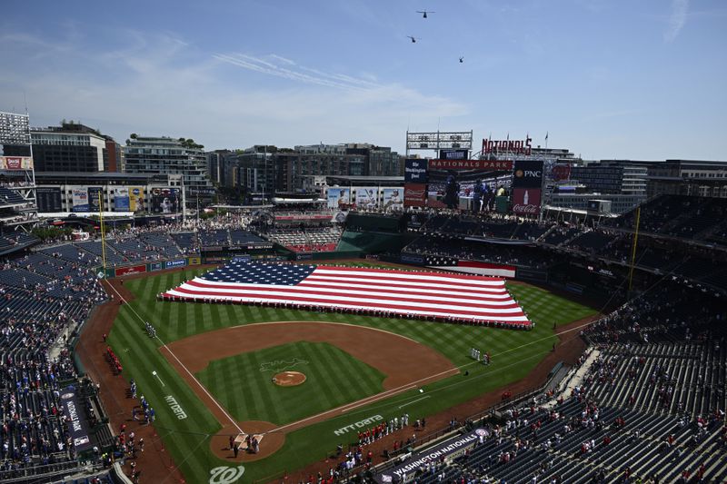 An American flag is displayed on the field during a flyover before a baseball game between the Washington Nationals and the New York Mets, Thursday, July 4, 2024, in Washington. (AP Photo/Nick Wass)