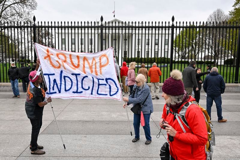 People set up a banner reading “Trump Indicted” outside the White House in Washington, March 31, 2023. A Manhattan grand jury voted to indict former President Donald Trump on Thursday afternoon, and he is likely to be arraigned on Tuesday, when the charges against him will be formally unveiled. (Kenny Holston/The New York Times)
                      