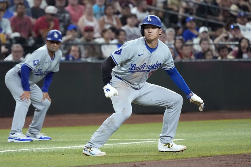 Los Angeles Dodgers' Shohei Ohtani of Japan, takes a lead off of third base against the Arizona Diamondbacks as Dodgers third base coach Dino Ebel, left, looks on during the second inning of a baseball game Friday, Aug. 30, 2024, in Phoenix. (AP Photo/Ross D. Franklin)