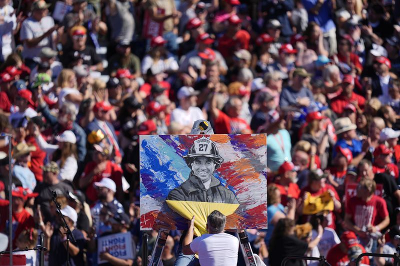 Artist Scott LaBaido unveils a painting of Corey Comperatore before Republican presidential nominee former President Donald Trump speaks at a campaign rally at the Butler Farm Show, Saturday, Oct. 5, 2024, in Butler, Pa. (AP Photo/Julia Demaree Nikhinson)