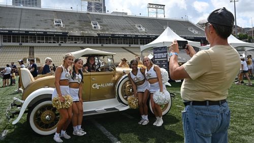 Members of Georgia Tech Cheerleading team pose with a fan in front of Ramblin' Wreck during Georgia Tech football’s annual Fan Day at Bobby Dodd Stadium, Saturday, August 5, 2023, in Atlanta. First Saturday on The Flats presented by Georgia’s Own Credit Union – Georgia Tech football’s annual Fan Day event – featured a plethora of other interactive on-field activities for the whole family, including the opportunity to run out of the Georgia Tech tunnel onto the field like the Yellow Jackets do on gameday, a football toss, ladder drills, combine and tailgate games, an agility course, field goal kicking, a uniform station, 360-degree photo booth and more. (Hyosub Shin / Hyosub.Shin@ajc.com)