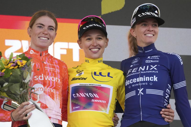 Tour de France Women winner Katarzyna Niewiadoma of Poland, wearing the overall leader's yellow jersey, Demi Vollering of The Netherlands, left and second place, and Pauliena Rooijakkers of The Netherlands, right and third place, celebrate on the podium after the eighth stage of the Tour de France Women cycling race with start in Le Grand-Bornand and finish in Alpe d'Huez, France, Sunday, Aug. 18, 2024. (AP Photo/Peter Dejong)