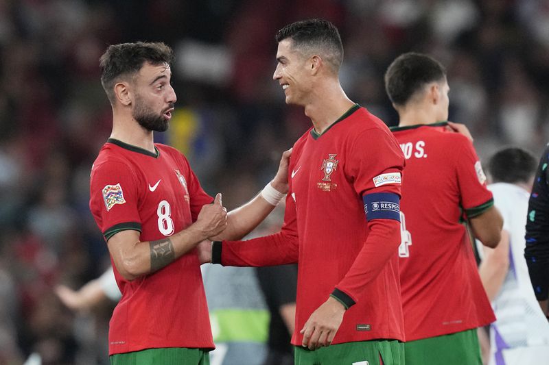 Portugal's Cristiano Ronaldo, centre, celebrates with Bruno Fernandes after the UEFA Nations League soccer match between Portugal and Scotland at the Luz stadium in Lisbon, Portugal, Sunday, Sept. 8, 2024. (AP Photo/Armando Franca)