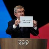 IOC president Thomas Bach holds the board Salt Lake City during the 142nd IOC session at the 2024 Summer Olympics, Wednesday, July 24, 2024, in Paris, France. Salt Lake City was confirmed as host for the 2034 Winter Games by International Olympic Committee. (AP Photo/Natacha Pisarenko, Pool)