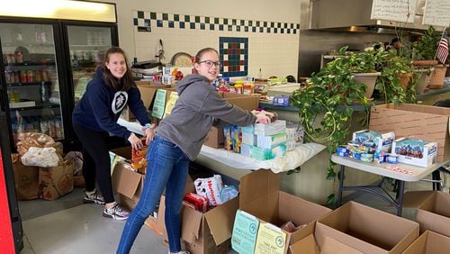 Georgia Alford and Winnie Alford, who are eighth and seventh graders at Sandy Springs Charter Middle School, respectively, place donated items for the community at Samad Mediterranean Grill and Market.  Photo courtesy Jennifer Lott