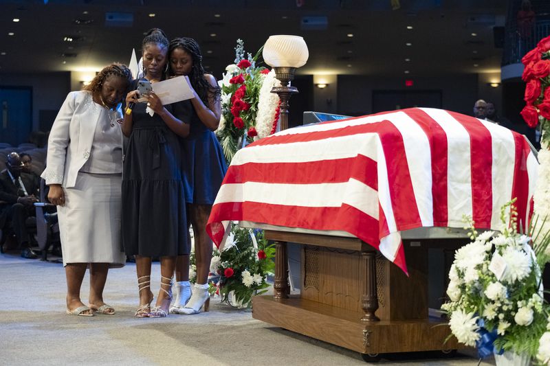 Meka Fortson (left) comforts Roger Fortson's cousins Brequita and Ricquita as they read a poem during the funeral Friday.
