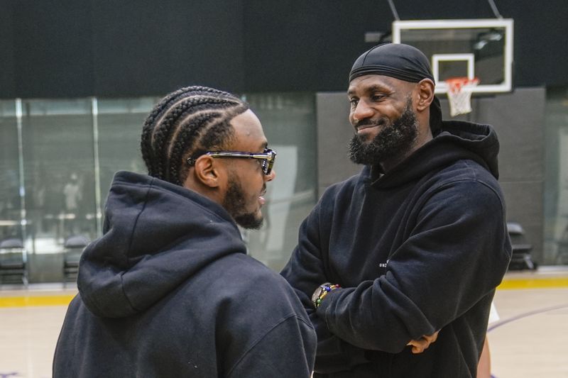 Los Angeles Lakers draft pick Bronny James, left, and his father, LeBron James, share a light moment as they arrive for the NBA basketball team's news conference in El Segundo, Calif., Tuesday, July 2, 2024 (AP Photo/Damian Dovarganes)