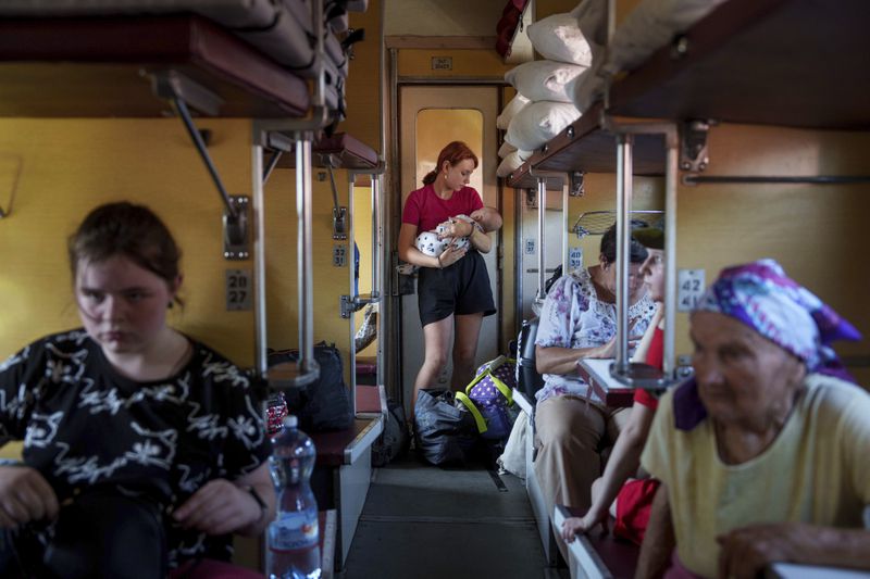 A girl calms her sister on an evacuation train in Pokrovsk, Donetsk region, Ukraine, Friday, Aug. 23, 2024. (AP Photo/Evgeniy Maloletka)