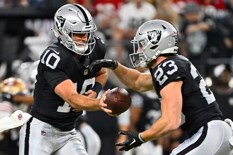 Las Vegas Raiders quarterback Nathan Peterman (10) hands off the ball to running back Dylan Laube (23) against the San Francisco 49ers during the first half of an NFL preseason football game, Friday, Aug. 23, 2024, in Las Vegas. (AP Photo/David Becker)