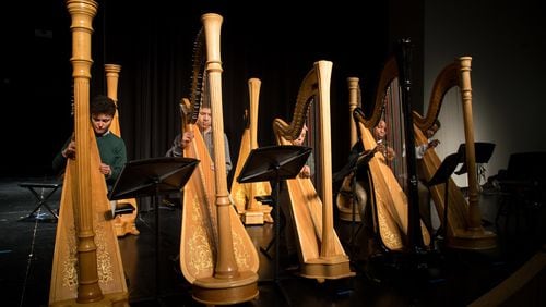 Drew Charter School freshman Aryka DeRose (left) plays her harp along with her classmates during practice. STEVE SCHAEFER / SPECIAL TO THE AJC