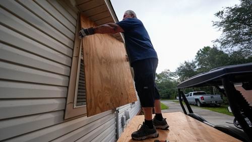 Dave McCurley boards up the windows to his home in advance of Tropical Storm Helene, expected to make landfall as a hurricane, in Ochlockonee Bay, Fla., Wednesday, Sept. 25, 2024. (AP Photo/Gerald Herbert)