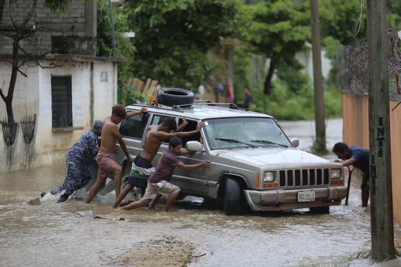 Residents work together to push a vehicle stuck on a street flooded by the passing of Hurricane John, in Acapulco, Mexico, Friday, Sept. 27, 2024. (AP Photo/Bernardino Hernandez)