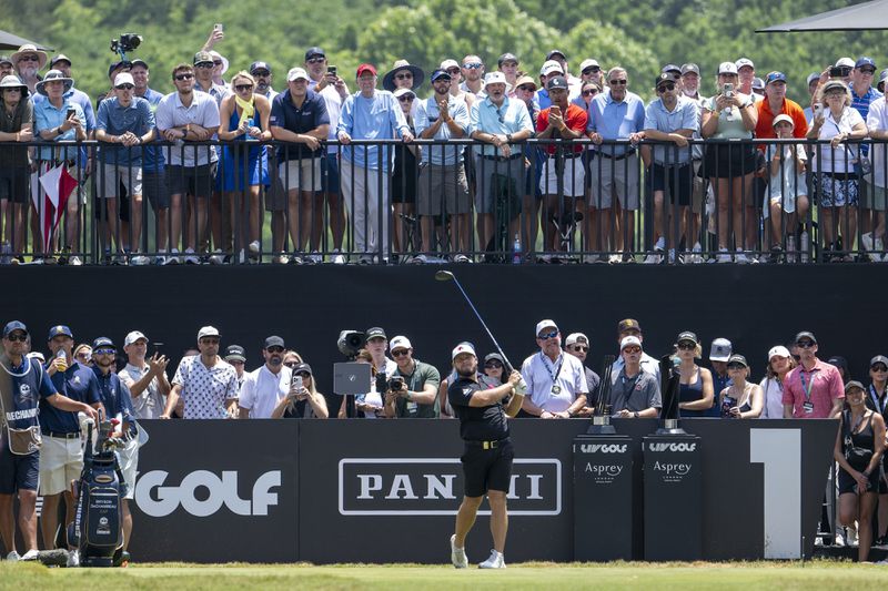 Tyrrell Hatton, center bottom, of Legion XIII, hits from the first tee as a gallery of fans look on during the final round of LIV Golf Nashville at The Grove, Sunday, June 23, 2024, in College Grove, Tenn. ( Charles Laberge/LIV Golf via AP)