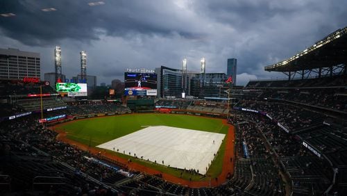 Ground crew workers cover the field as the game between the Atlanta Braves and the Cincinnati Reds is delayed at Truist Park on Tuesday, July 23, 2024, in Atlanta. It was eventually postponed. 
(Miguel Martinez/ AJC)