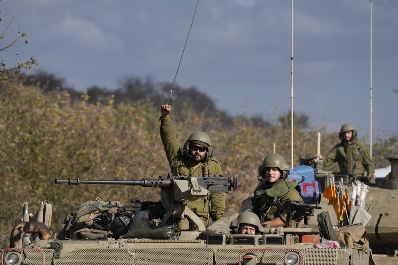 An Israeli soldier raises his fist from a moving APC in northern Israel near the Israel-Lebanon border, Tuesday, Oct. 1, 2024. (AP Photo/Baz Ratner)