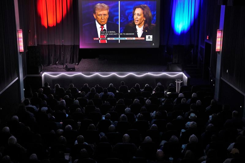 People watch the presidential debate between Republican presidential nominee former President Donald Trump and Democratic presidential nominee Vice President Kamala Harris at a 97-year-old movie theater Tuesday, Sept. 10, 2024, in Shawnee, Kan. (AP Photo/Charlie Riedel)