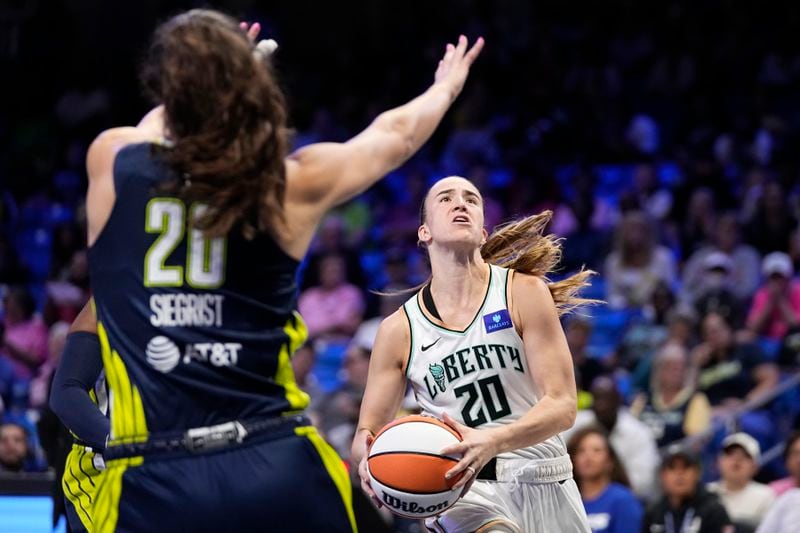 New York Liberty's Sabrina Ionescu, right, drives to the basket as Dallas Wings' Maddy Siegrist, left, defends in the second half of a WNBA basketball game, Thursday, Sept. 12, 2024, in Arlington, Texas. (AP Photo/Tony Gutierrez)