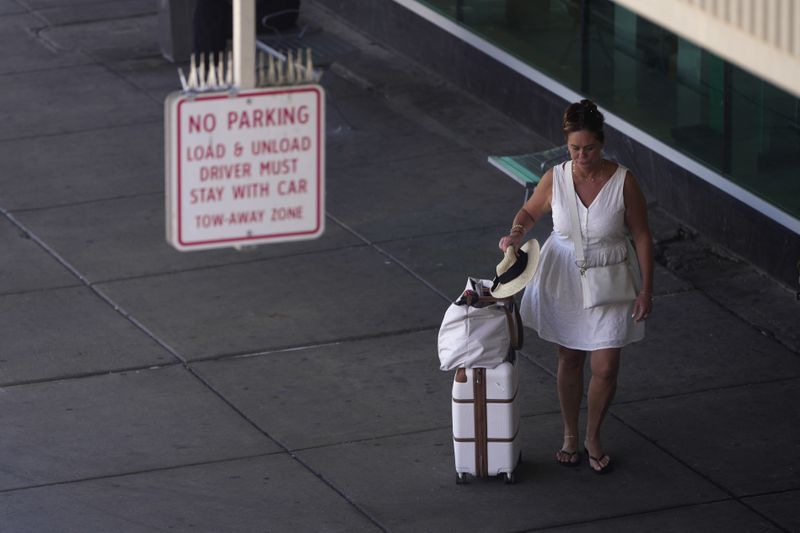 A travelers walks outside the Philadelphia International Airport, Wednesday, July 3, 2024, in Philadelphia. (AP Photo/Matt Slocum)