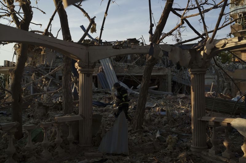 A firefighter collects fragments of a rocket after a Russian strike on Sapphire hotel in Kramatorsk, Donetsk region, Ukraine, on Sunday, Aug. 25, 2024. Reuters news agency said Sunday one of their journalists covering the war in Ukraine was missing and two others were hospitalized after a Russian missile strike on a hotel in the eastern Ukrainian city of Kramatorsk. (AP Photo/Evgeniy Maloletka)