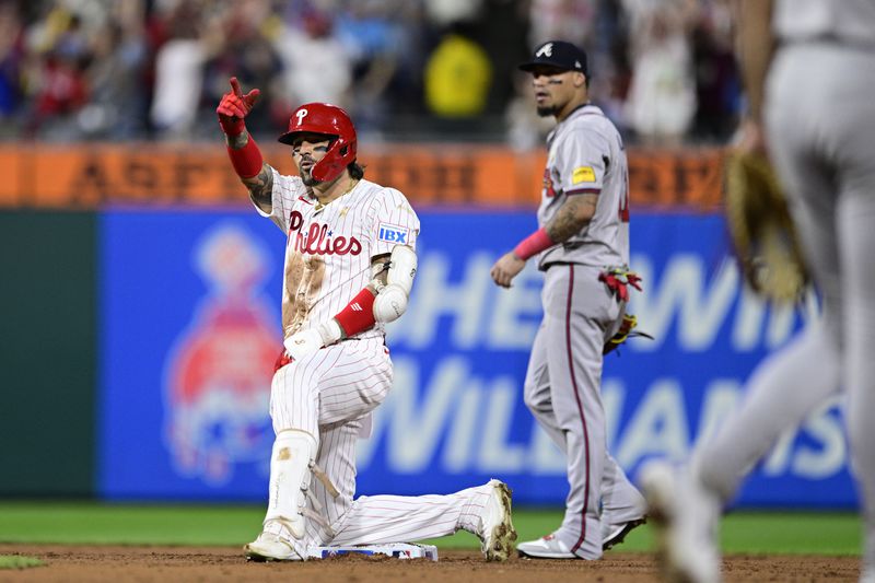 Philadelphia Phillies' Nick Castellanos, left, reacts after hitting an two-run double off Atlanta Braves' Spencer Schwellenbach during the sixth inning of a baseball game, Sunday, Sept. 1, 2024, in Philadelphia. (AP Photo/Derik Hamilton)