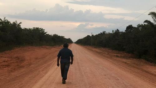 FILE - A man walks down an unpaved stretch of highway BR-319 in the Brazilian Amazon between the cities of Manaus and Porto Velho on Aug. 10, 2018. A Brazilian federal court on July 24, 2024, halted progress on the project paving this dirt highway that connects the major city of Manaus with populous regions, citing the likelihood it will contribute to climate change. (AP Photo/Fabiano Maisonnave, File)