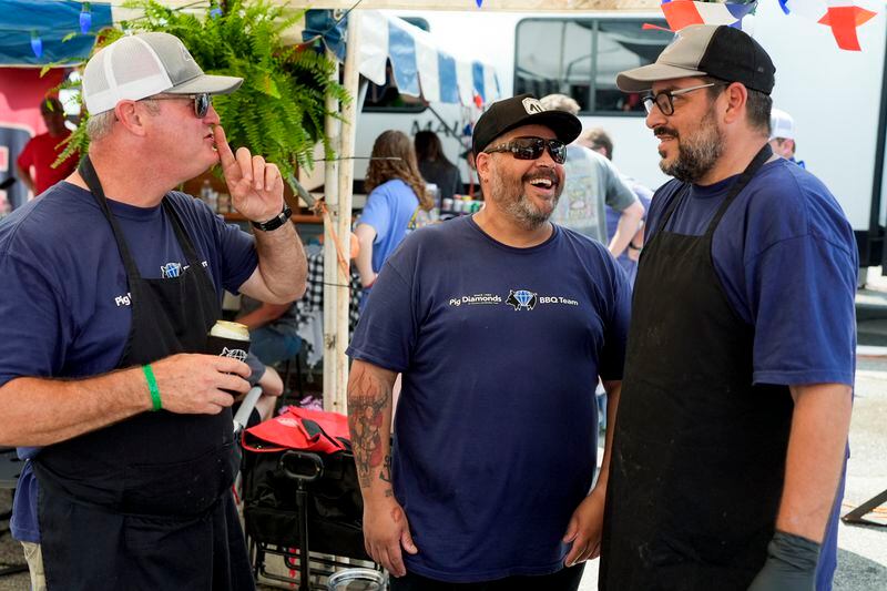 John Borden, left, Hugo Costa and Adriano Pedro, right, of the Pig Diamonds BBQ Team share a laugh at the World Championship Barbecue Cooking Contest, Friday, May 17, 2024, in Memphis, Tenn. The team is comprised of members from Brazil and the United States. (AP Photo/George Walker IV)
