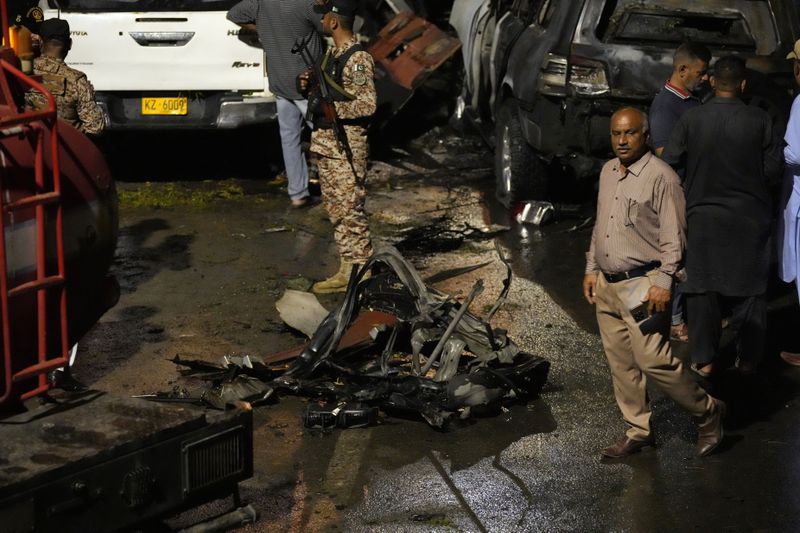 Security officials examine the site of an explosion that caused injures and destroyed vehicles outside the Karachi airport, Pakistan, early Monday, Oct. 7, 2024. (AP Photo/Fareed Khan)