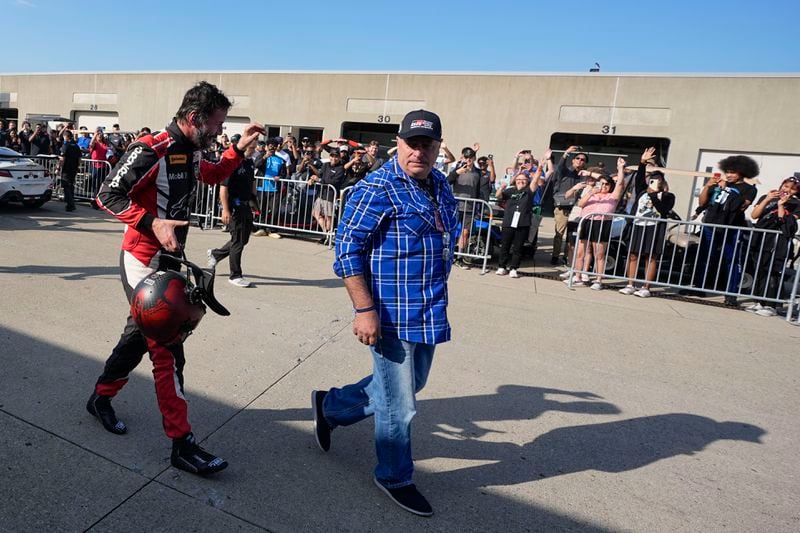 Keanu Reeves waves to fans in the garage area following a GR Cup Series auto race at Indianapolis Motor Speedway, Saturday, Oct. 5, 2024, in Indianapolis. (AP Photo/Darron Cummings)