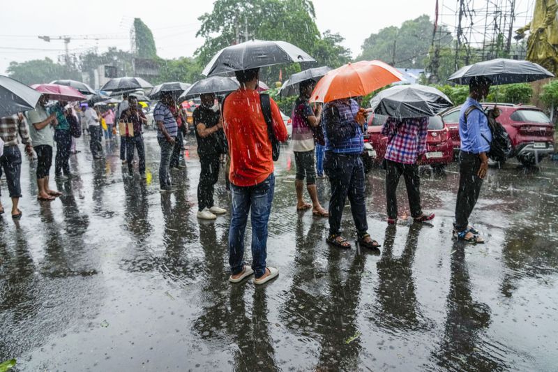 Stranded passengers await transport in Kolkata, India, as rain continues after cyclone Remal made a landfall near Bangladesh-India border, Monday, May 27, 2024. (AP Photo/Bikas Das)