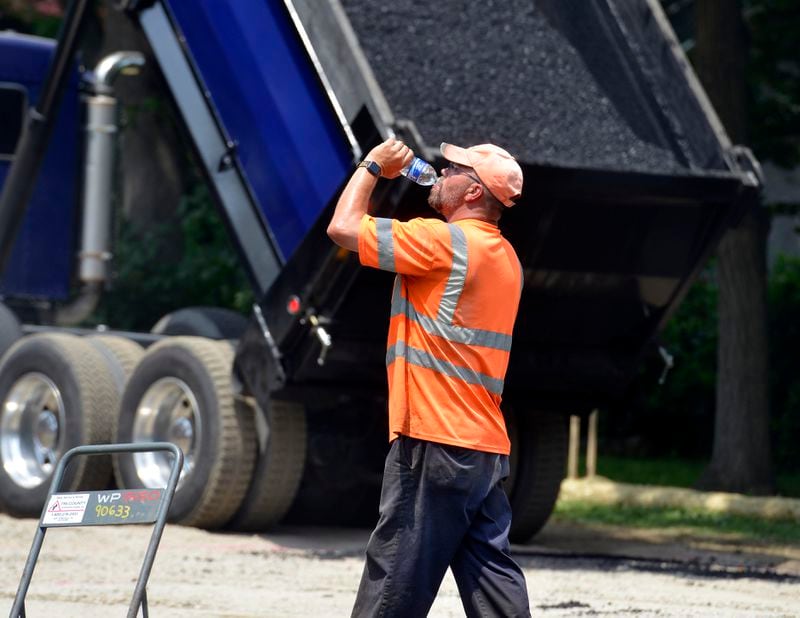 Chad Welch of Holyoke chugs water while laying asphalt at Kenefick park in Springfield, Mass. (Don Treeger/The Republican via AP)