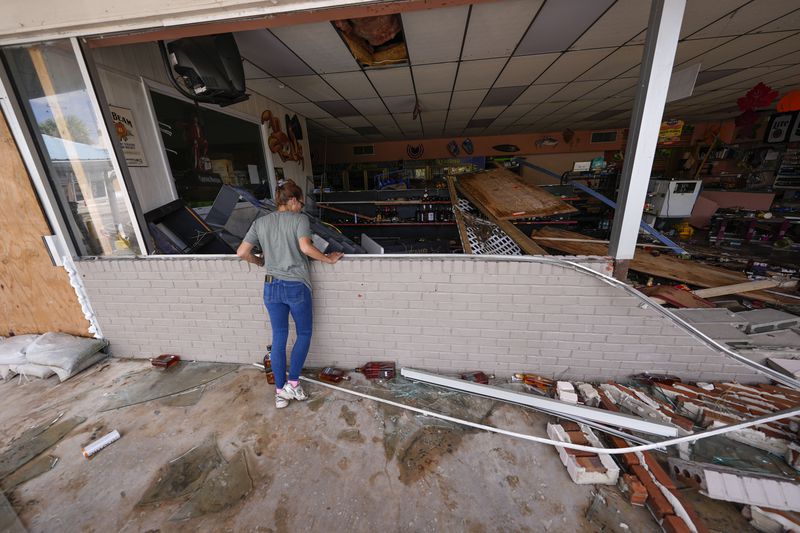 Karen Hurne surveys the damaged Swami Spirits in the aftermath of Hurricane Helene, in Cedar Key, Fla., Friday, Sept. 27, 2024. (AP Photo/Gerald Herbert)