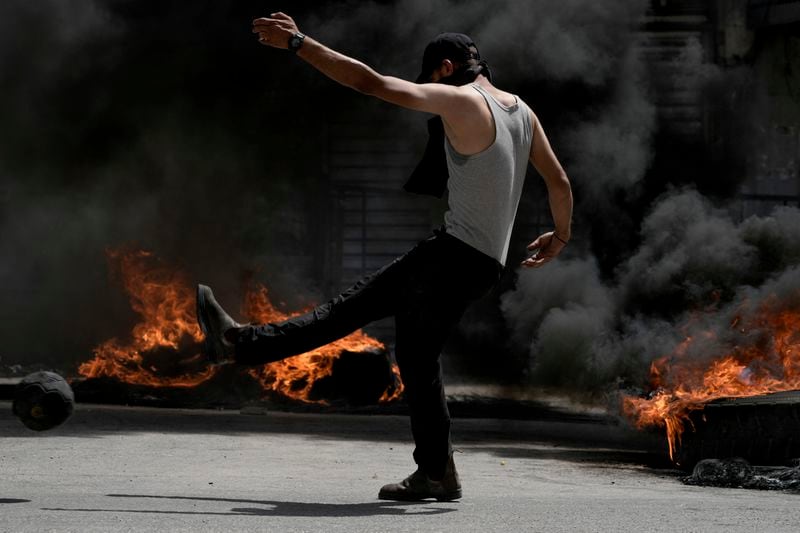 A Palestinian demonstrator burns tires next to a model of a rocket during clashes with Israeli forces in the West Bank city of Jenin, Wednesday, May 22, 2024. (AP Photo/Majdi Mohammed)