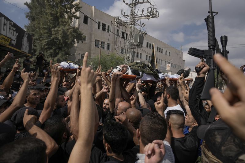 Mourners, some armed, carry the bodies of Palestinian men who were killed during an Israeli military operation, draped in the Islamic Jihad militant group flags, during their funeral in Jenin, West Bank, Friday, Sept. 6, 2024. (AP Photo/Majdi Mohammed)