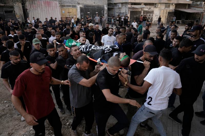 Mourners carry body of Wassim Anbar, wrapped with Islamic Jihad flag, during the funeral of three Palestinians who were killed by an Israeli airstrike in the occupied West Bank refugee camp of Tulkarem, Thursday, Aug. 22, 2024. The Palestinian Health Ministry says three people have been killed in an Israeli strike in the occupied West Bank. (AP Photo/Majdi Mohammed)