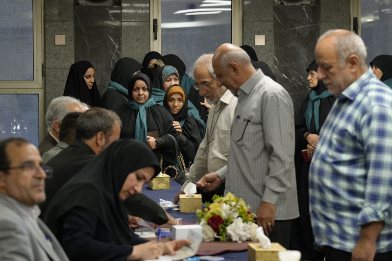 Iranian citizens wait in queue to cast their votes during the presidential election at a polling station inside the Iranian embassy in Baghdad, Iraq, Friday, June 28, 2024. Iranians are voting in a presidential election to replace the late President Ebrahim Raisi, killed in a helicopter crash in May along with the country's foreign minister and several other officials. (AP Photo/Hadi Mizban)