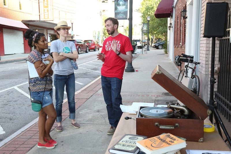 Preservationist and architect Kyle Kessler speaks with passersby last Wednesday about his campaign to save the historic building. Kessler cranked a portable Victrola Talking Machine to play songs recorded in the building in 1923. (Tyson Horne / Tyson.Horne@ajc.com)