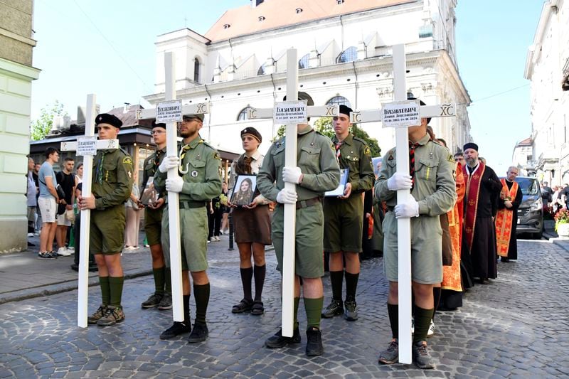 People hold crosses during the funeral ceremony for family members of Yaroslav Bazylevych in Lviv, Ukraine, Friday, Sept. 6, 2024. Bazylevych's wife Yevgenia and their three daughters - Darina, 18, Emilia, 7, and Yaryna, 21 - were killed in Wednesday's Russian missile attack. (AP Photo/Mykola Tys)